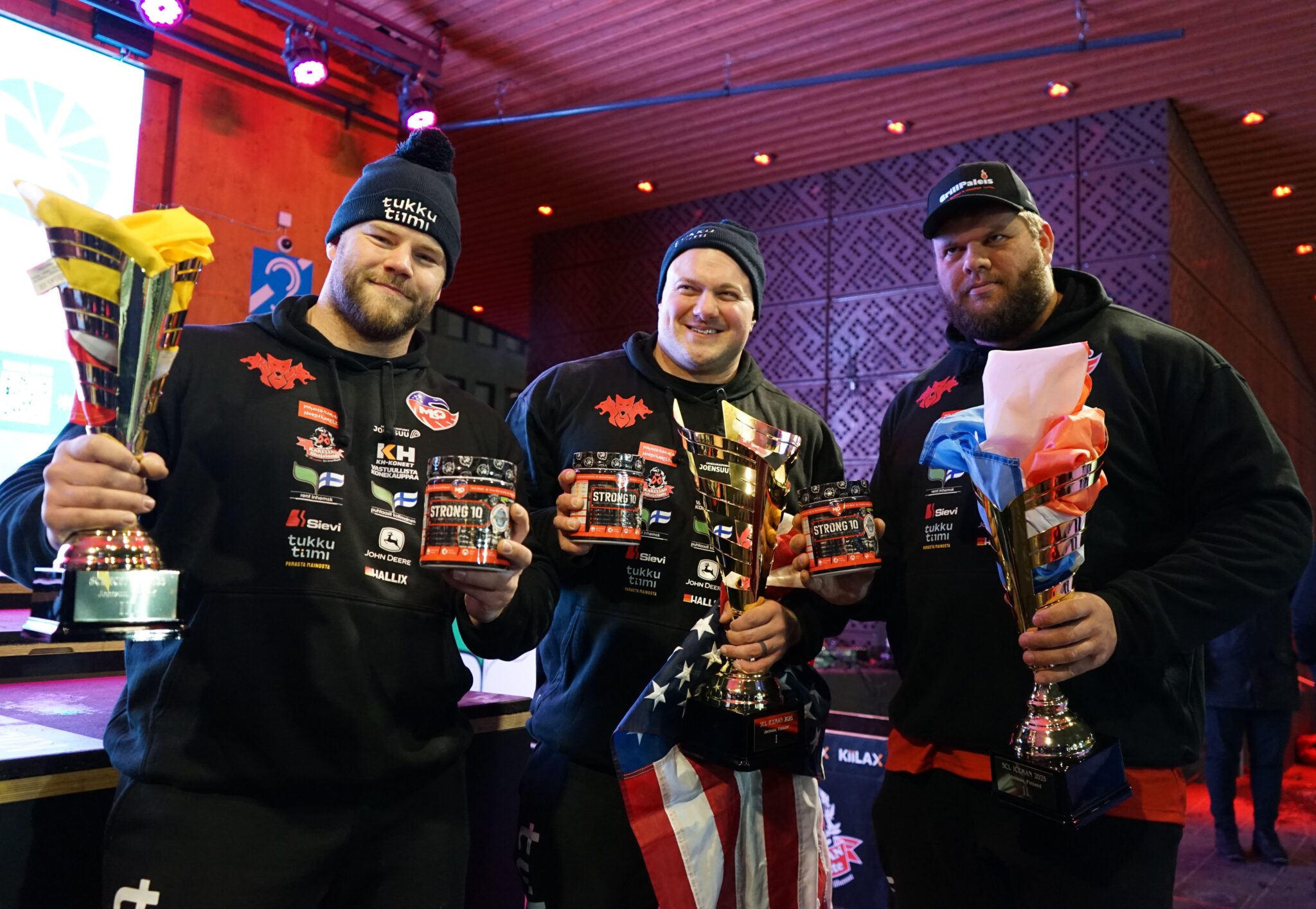 Brian Kichton, Kevin Hazeleger, and Patrick Eibel celebrating their podium finish at ICEMAN 2025, holding trophies and supplement containers.